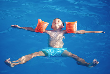 Cute caucasian boy swimming in the pool.