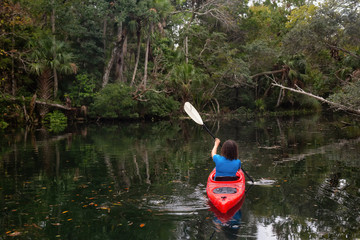 Adventurous girl kayaking on a river covered with trees. Taken in Chassahowitzka River, located West of Orlando, Florida, United States.