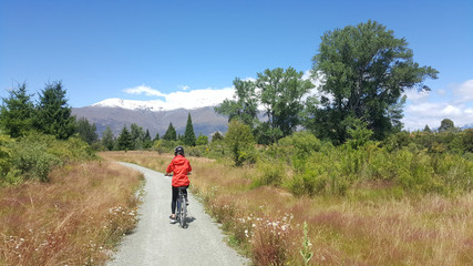 Tourist enjoys beautiful countryside scenery in New Zealand. Person riding bicycle. Active lifestyle image of people having fun. Lifestyle image of a person riding bike in natural landscape.