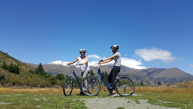Couple enjoys beautiful countryside scenery in New Zealand. Romantic couple riding bicycle Active lifestyle image of people having fun. Happiness image of a young couple.