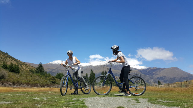 Couple enjoys beautiful countryside scenery in New Zealand. Romantic couple riding bicycle Active lifestyle image of people having fun. Happiness image of a young couple.