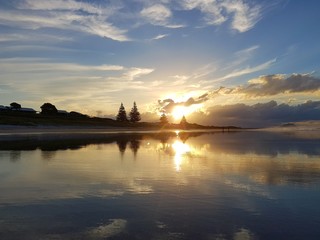 An epic sunset taken in New Zealand. The sun rays are beautiful. The ocean water reflects the sun light. This is a very peaceful landscape photo. It is suitable for background use.