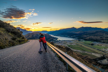 Fototapeta na wymiar Couple enjoys beautiful queenstown scenery in New Zealand. Romantic couple goes on road trip. A pair of couple goes on honeymoon in natural landscape. Happiness image of a young couple.