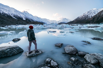 Person, die auf Eissee und Schneebergen am Tasman Lake, Aoraki Mount Cook National Park, Neuseeland, steht.