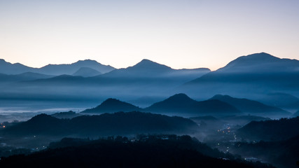 Fototapeta premium This photo was taken on a mountain summit in Taiwan, Asia. It was cold early morning. As the sunrise, one can see the shadows and silhouette of layers of mountains and ghostly clouds.