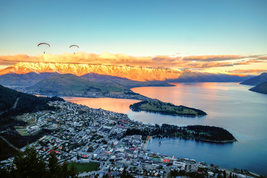 View of Queenstown and The Remarkables, Queenstown New Zealand. There are paragliders flying above the village. This is a popular tourist destination. Winter is great season to visit New Zealand.