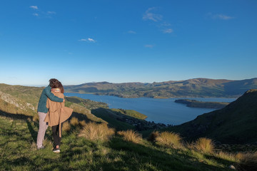 Fototapeta na wymiar Couple enjoys beautiful port hills Crater Rim near Christchurch in New Zealand. Romantic couple goes on adventure. Happiness image of a young people going on a day trip.