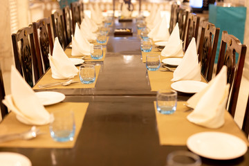 Selected focus of empty glass of water on dinner table with napkin.