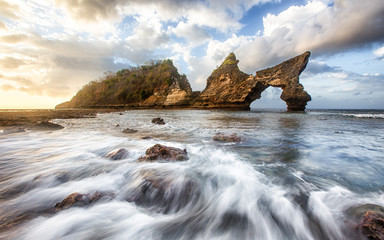 Obraz na płótnie Canvas This is taken in Bali, Indonesia. It was taking during sunrise. There are huge beautiful cliff, arches and caves around this area. The ocean waves are very strong. This makes a beautiful background.