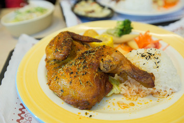 A plate of roasted chicken with rice on bright colored plate