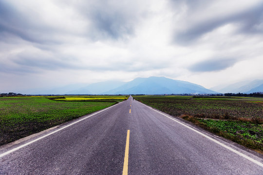 A straight road leading into the distance. This image was taken in a countryside of Taiwan. A straight road represents journey, direction, future, forward and travel. It is suitable for background.