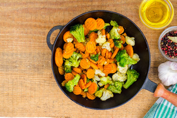 Stewed vegetables in oil on old pan, wooden table