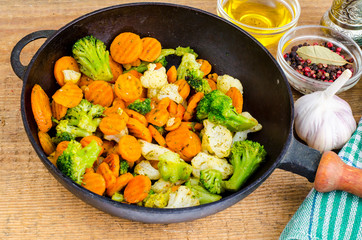 Stewed vegetables in oil on old pan, wooden table