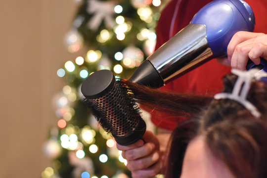 Hairdresser drying long hair with hair dryer. Making hairstyle for Christmas holidays. Concept of hair drying, barber salon, female stylist