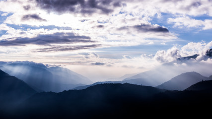 Obraz na płótnie Canvas Taken on the peak of a mountain in Taiwan, one can see layers and layers of mountain ranges from the distance. The light rays are strong and stunning. The image is perfect for background use.