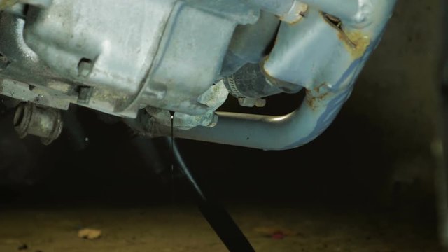 Close-up of the motorcycle engine crankcase with merging old waste oil into a plastic canister