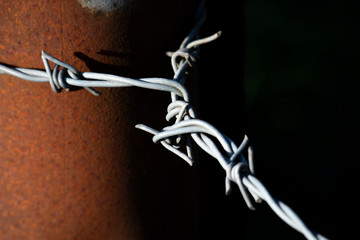 Barbed wired fence secured to post providing security to farmland in rural Hampshire