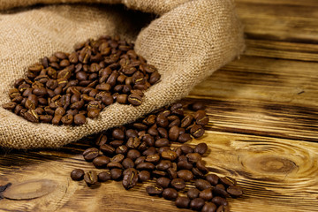 Roasted coffee beans on sackcloth on wooden table