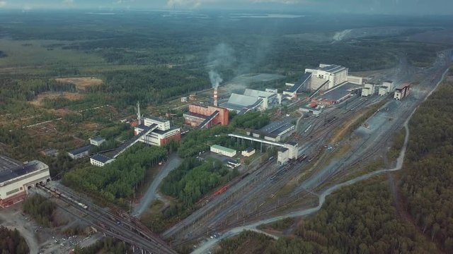Aerial view of plant industrial buildings with tall smokestacks surrounded by forest. Production system.