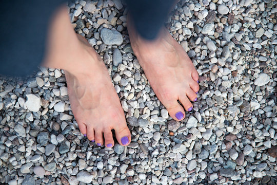A beautiful girls feet at the beach, purple nail polish