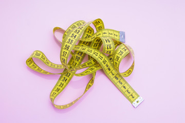 diet and slimming concept, yellow metric tape on pink background
