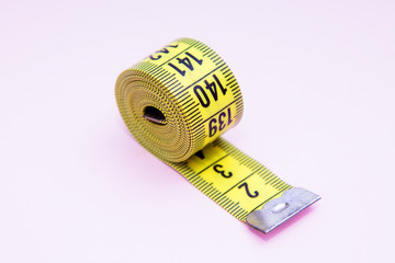 diet and slimming concept, yellow metric tape on pink background