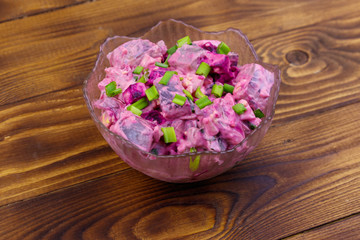 Obraz na płótnie Canvas Tasty salad with herring, beetroot, eggs, onion and mayonnaise on wooden table