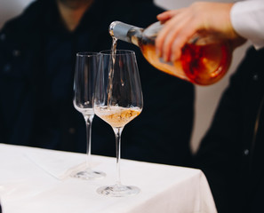 Pour rose wine from glass into glass.