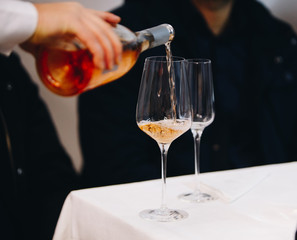 Pour rose wine from glass into glass.