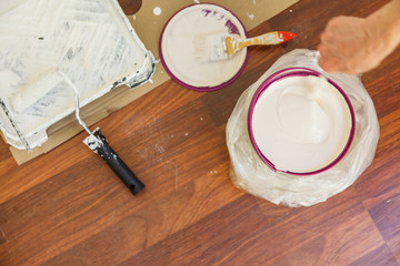 Person mixing white paint in bucket.