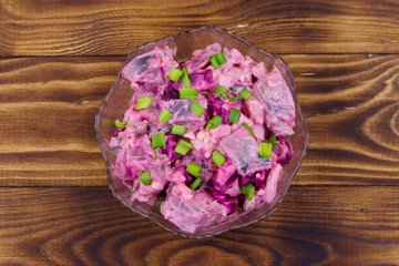Tasty salad with herring, beetroot, eggs, onion and mayonnaise on wooden table. Top view