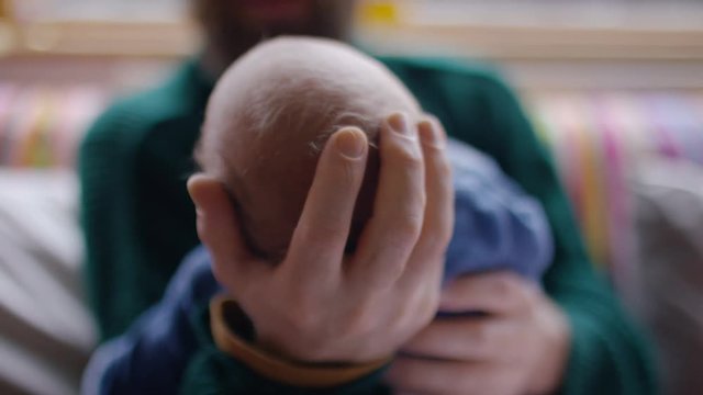 Hands of a father cradling his baby's head as he looks at him lovingly