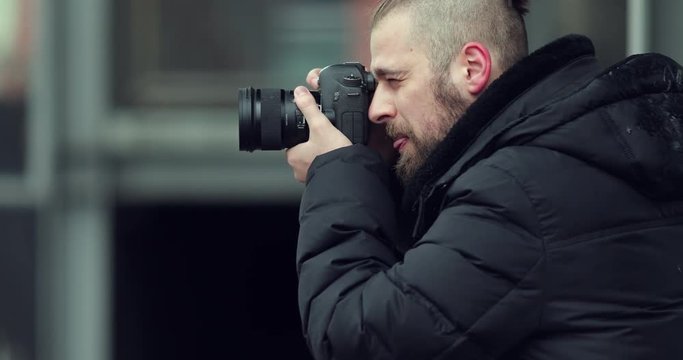 Bearded photographer taking pictures on the street with his camera and look at what he captured. 4K Footage - Video