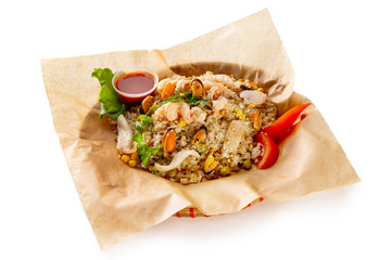 Traditional vietnamese fried rice with seafood and shrimps served with hot sauce at wicker plate isolated at white background.
