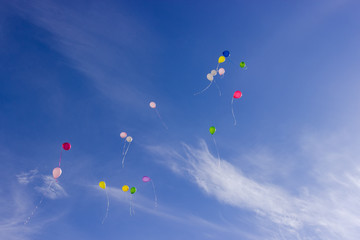 Multicolored balloons flying in the sky with cirrus clouds