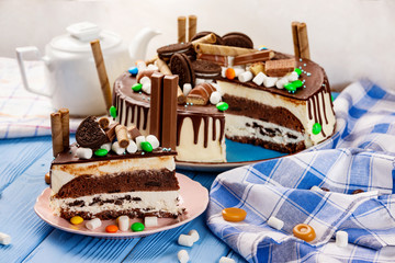 Plate of sweet chocolate cake with bisquits and candies at decorated wooden table background.
