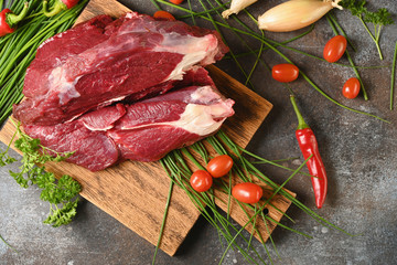 Fresh dark meat with ingredients for cooking on brown wooden cutting board. Hunting composition. Wildanimal hunting.