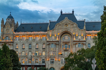 Obraz premium Beautiful old building in the city of Budapest in the evening surrounded by trees