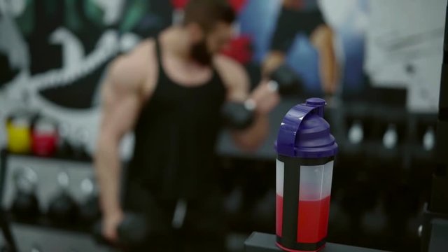 Muscular ripped guy with beard working out bicepses with dumbbells, heavy set on arms.