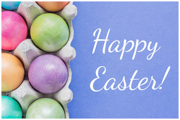 Multicolored easter eggs in a box on blue background, Top view. Greeting card Happy Easter
