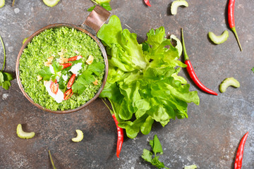 Green vegetarian soup in copper cup on dark background. Horizontal.