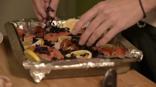 Closeup of girl's hand in home kitchen sprinkle chopped regen dish on a tray. Healthy home cooking