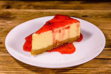 White plate with cheesecake New York and raspberry jam on wooden table