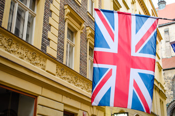 Fototapeta na wymiar British flag hangs on a building. Old-fashioned european buildings at the background.