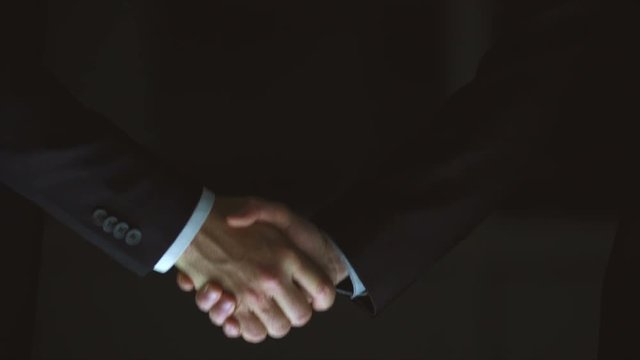 The two male handshake on the dark background. slow motion