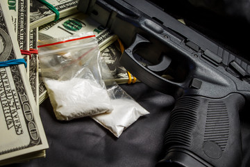 Drug in the form of white powder in plastic bags on packs of dollars with a gun