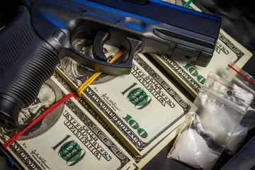 Drug in the form of white powder in plastic bags on packs of dollars with a gun