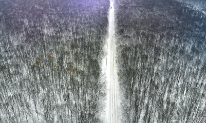 Aerial. Beautiful rural country road between winter forest. Top view.
