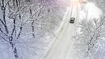 Aerial. Car on a rural snowy country road. Driving in winter.