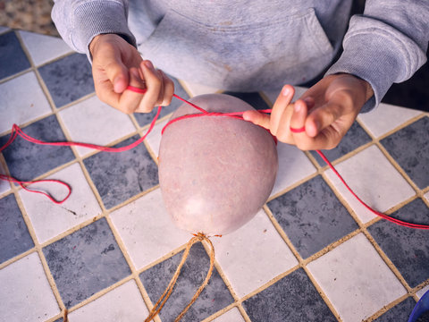 Elderly person sewing natural sausage